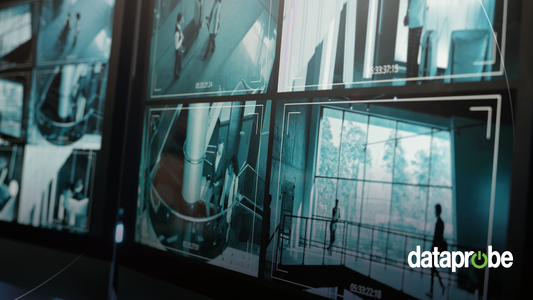 A close-up of a dark security monitor displaying multiple CCTV feeds with a teal tint and a white target overlay, with a 'dataprobe' watermark in the bottom right corner.