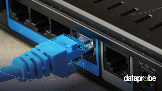 A close-up of a blue Ethernet cable RJ45 connector plugged into a black network switch or router port, with a dataprobe watermark in the bottom right corner.